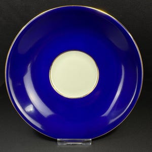 Peut inclure: Une soucoupe bleu cobalt avec un centre crème et un bord doré. La soucoupe est ronde et a une finition brillante. Le design est simple et élégant, adapté à un service à thé ou à café.