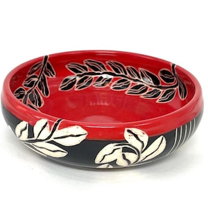 Intricately carved ceramic bowl, with leaves and detailed graphic design in a beautiful deep red, sgraffito