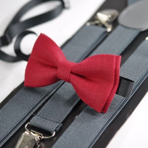 Puede incluir: Un conjunto de tirantes grises con una pajarita roja. Los tirantes tienen clips ajustables y están hechos de una tela suave y cómoda.