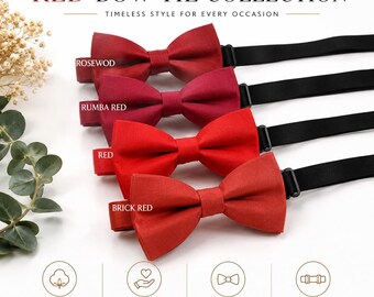 May include: A collection of four pre-tied bow ties in shades of rosewood, rumba red, red, and brick red. Each bow tie features a black adjustable strap. The image includes text labels for each color and icons indicating cotton material and features.