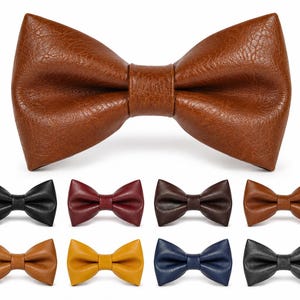 May include: A large tan bow tie with a textured surface is centered above eight smaller bow ties in various colors including black, burgundy, dark brown, light brown, mustard yellow, navy blue, and grey, all featuring a consistent textured finish.