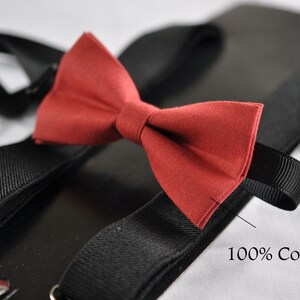 Puede incluir: Tirantes elásticos negros con una pajarita roja. La pajarita está hecha de 100% algodón.