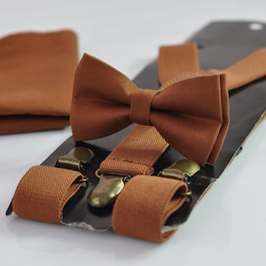 Peut inclure: Un ensemble de nœud papillon et de bretelles marron. Le nœud papillon est fait d'un tissu doux et a une forme classique. Les bretelles sont réglables et ont des clips métalliques.