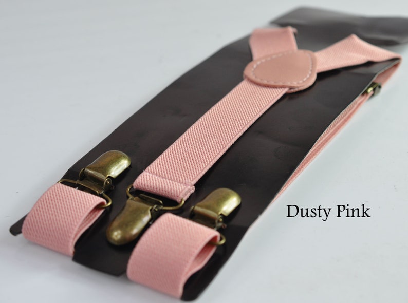 Peut inclure: Bretelles rose poussi&eacute;reux avec des clips m&eacute;talliques dor&eacute;s. Les bretelles sont faites d'un tissu doux et tiss&eacute; et ont un design classique en Y.