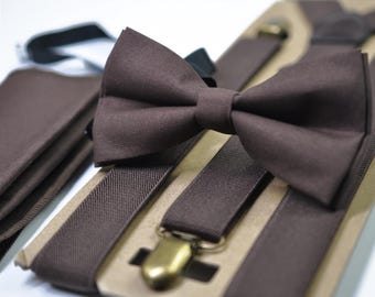 May include: A brown bow tie, suspenders, and a pocket square set. The bow tie is pre-tied and sits atop the suspenders, which have gold-colored metal clasps. The pocket square is folded neatly. The set is displayed on a cardboard backing.