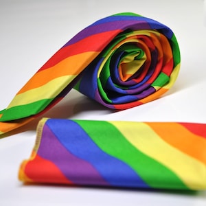 May include: A rainbow tie and pocket square set. The tie is rolled up and the pocket square is folded. Both are made of a soft, colorful fabric.