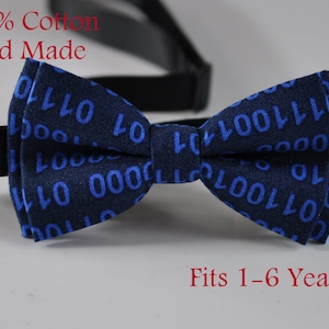 Może przedstawiać: Niebieski krawat muszka z białą gumką. Muszka jest wykonana w 100% z bawełny i jest ręcznie robiona. Ma wzór niebieskich "1" i "0" na ciemnoniebieskim tle. Muszka jest odpowiednia dla dzieci w wieku od 1 do 6 lat.