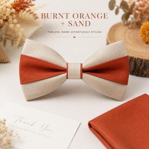 Puede incluir: Una pajarita con un diseño bicolor en tela naranja quemado y beige arena. El nudo central es beige arena, flanqueado por franjas horizontales en naranja quemado y arena. Un pañuelo de bolsillo a juego en naranja quemado está cerca.