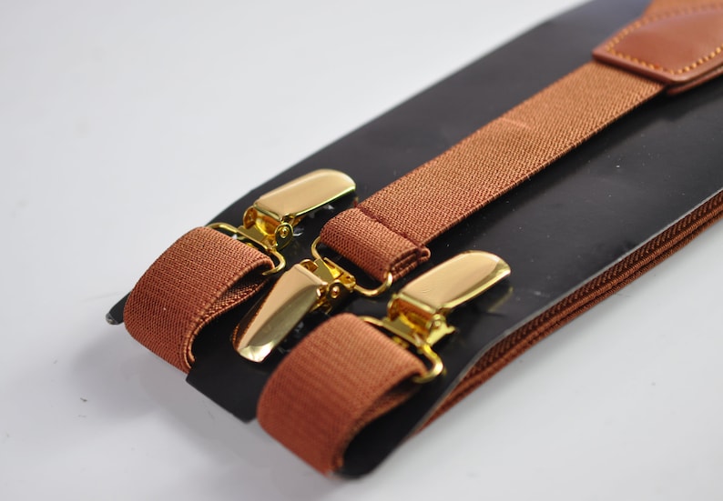 May include: Brown suspenders with gold metal clips. The suspenders are packaged on a black card with a brown leather trim.