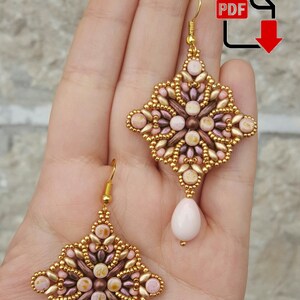 Può includere: Un paio di orecchini con perline dorate e rosa con un ciondolo a forma di lacrima. Gli orecchini hanno la forma di uno scoppio di stelle e un design delicato e intricato.