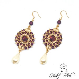 Peut inclure: Une paire de boucles d'oreilles en perles dor&eacute;es et bordeaux avec une goutte de perle. Les boucles d'oreilles pr&eacute;sentent un motif rond en perles avec une petite pierre iris&eacute;e au centre.