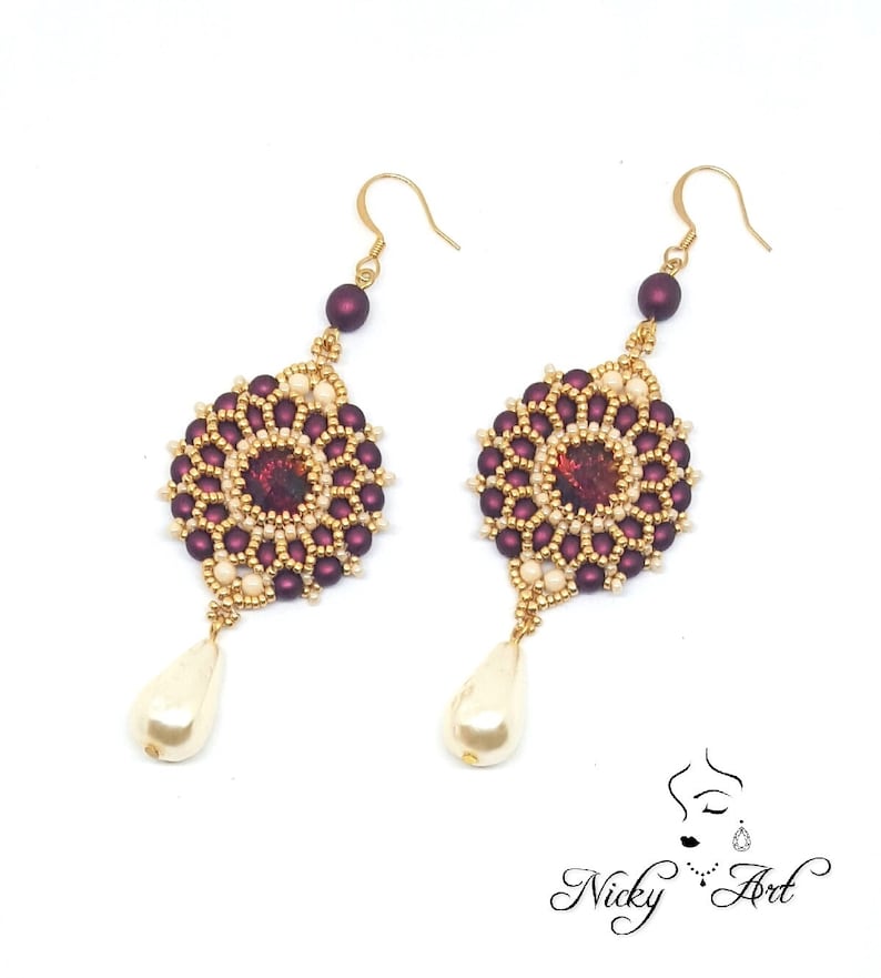 Peut inclure: Une paire de boucles d'oreilles en perles dor&eacute;es et bordeaux avec une goutte de perle. Les boucles d'oreilles pr&eacute;sentent un motif rond en perles avec une petite pierre iris&eacute;e au centre.