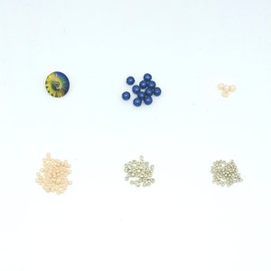 Peut inclure: Assortiment de perles de diff&eacute;rentes couleurs et tailles. Il y a des perles bleues, argent&eacute;es et cr&egrave;me.