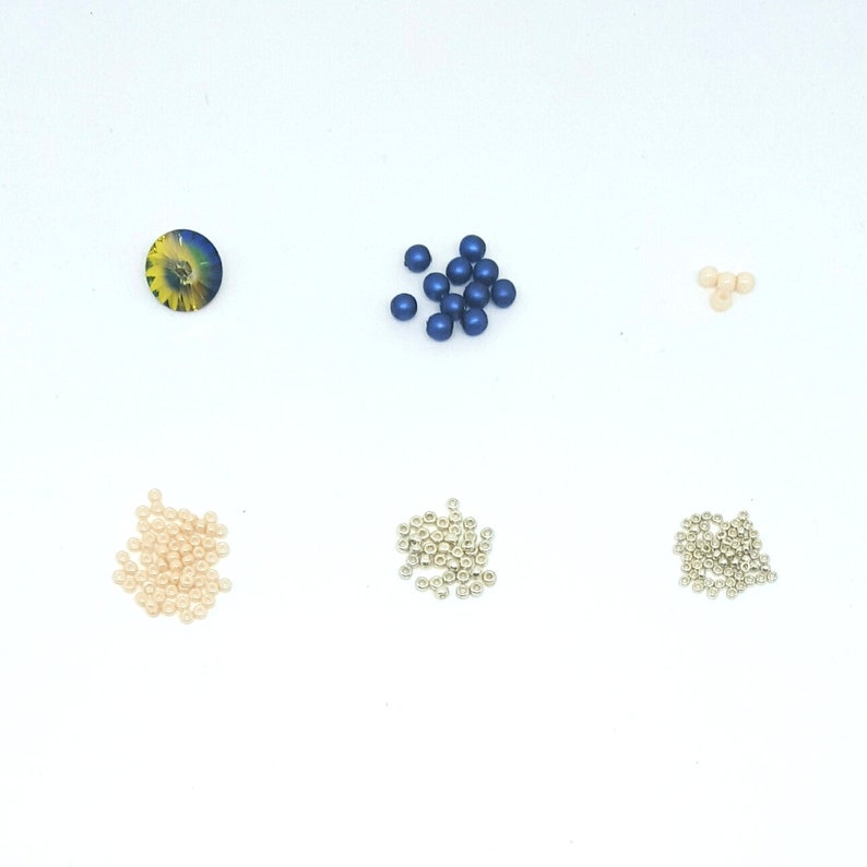 Peut inclure: Assortiment de perles de diff&eacute;rentes couleurs et tailles. Il y a des perles bleues, argent&eacute;es et cr&egrave;me.