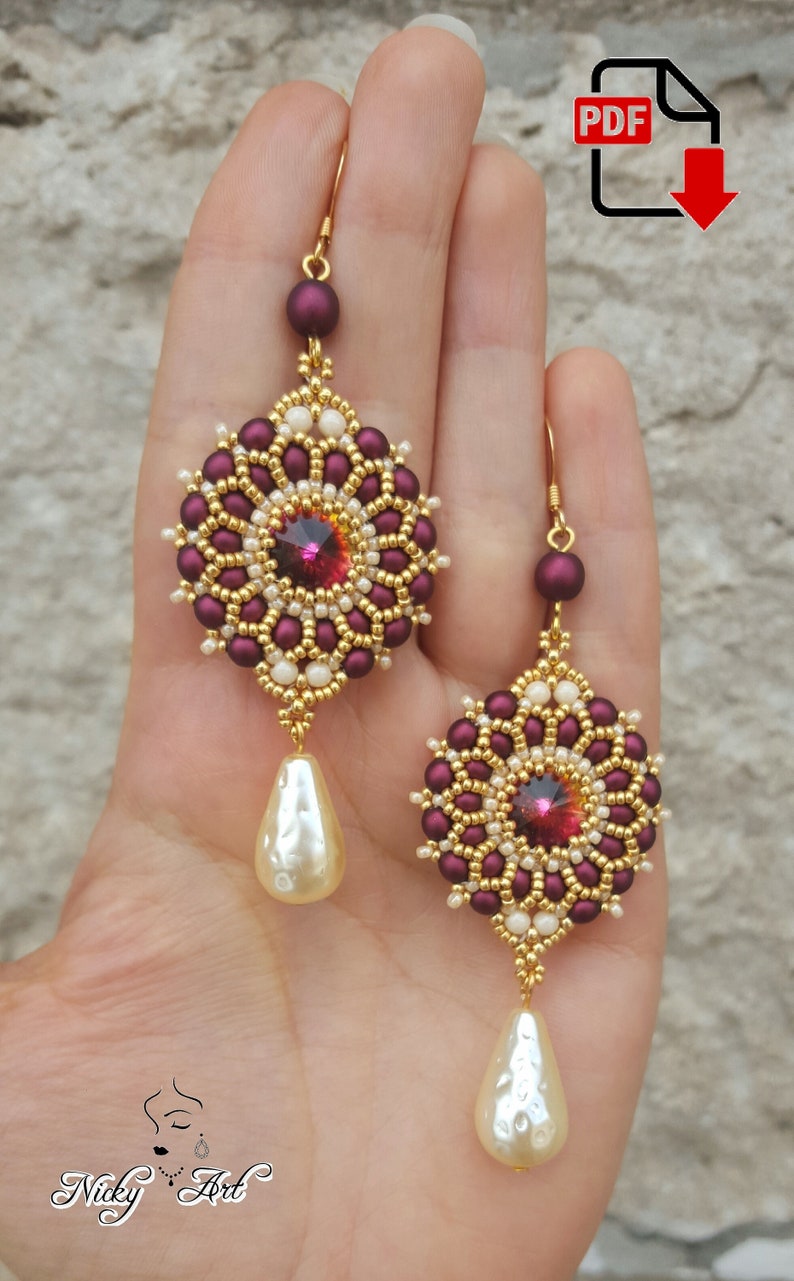 Peut inclure: Une paire de boucles d'oreilles en perles avec un motif de couleur bordeaux et or. Chaque boucle d'oreille pr&eacute;sente un motif rond en perles avec un cristal rouge au centre et une goutte nacr&eacute;e suspendue en dessous.