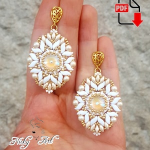 May include: A pair of white and gold beaded earrings with a round, iridescent stone in the centre of each earring. The earrings are hanging from a gold hook.