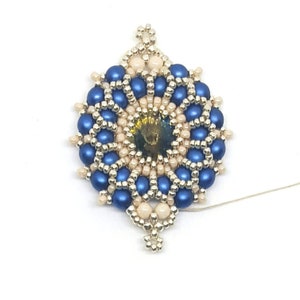 Peut inclure: Un pendentif en perles bleues et cr&egrave;me avec un &eacute;l&eacute;ment central dor&eacute;. Le pendentif est attach&eacute; &agrave; un fil blanc.
