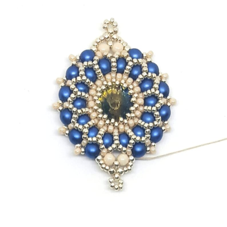 Peut inclure: Un pendentif en perles bleues et cr&egrave;me avec un &eacute;l&eacute;ment central dor&eacute;. Le pendentif est attach&eacute; &agrave; un fil blanc.
