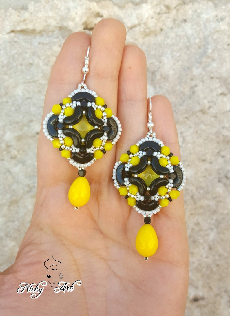 May include: A pair of black and yellow beaded earrings with a teardrop-shaped yellow bead dangling from each earring.