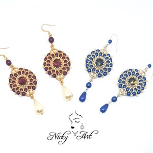 Peut inclure: Trois paires de boucles d'oreilles pendantes avec des attaches en m&eacute;tal dor&eacute; et un pendentif en forme de larme de perle. Les boucles d'oreilles pr&eacute;sentent un motif rond perl&eacute; avec un cristal central. Les perles sont dans des tons de bordeaux, bleu et cr&egrave;me.