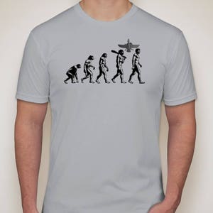 May include: A gray t-shirt with a black and white graphic of the evolution of man, ending with a man holding a baseball bat and a winged symbol above his head.
