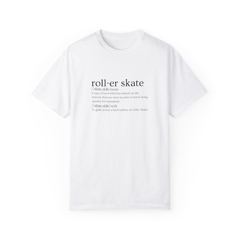 May include: White t-shirt with a black graphic design that defines the word "roller skate" as a type of boot with four wheels on the bottom that you wear to travel quickly for enjoyment. The graphic also defines the word as a verb, "to glide across a hard surface on roller skates."