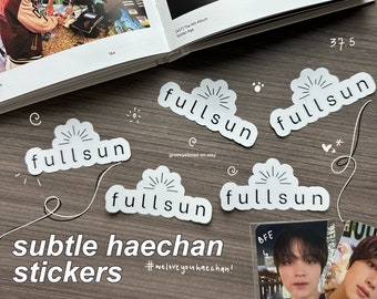 Puede incluir: Cinco pegatinas blancas en forma de nube con el texto "fullsun" en letras negras. Las pegatinas están sobre una superficie de madera marrón. El texto "#welove you haechan!" está escrito en negro sobre la superficie.