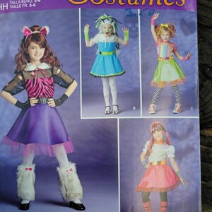 May include: A sewing pattern envelope featuring four costume designs for children. The costumes include a purple skirt with a pink zebra print top, a blue plaid dress, a rainbow striped top with a green skirt, and a white top with a pink skirt.