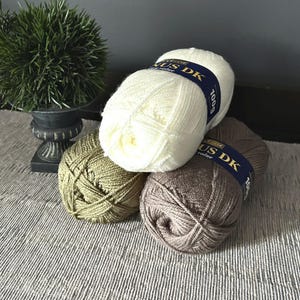 The balls of yarn, that were used in creating this crochet pattern, are sitting on a table.