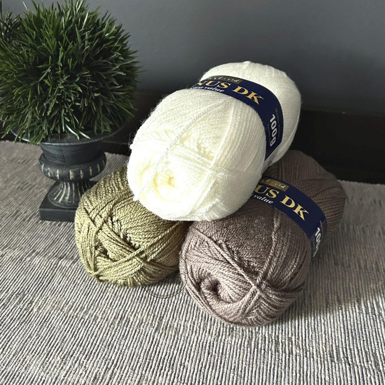 The balls of yarn, that were used in creating this crochet pattern, are sitting on a table.