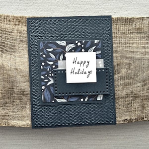 A finished card, from this card making kit, sitting on a wooden board.