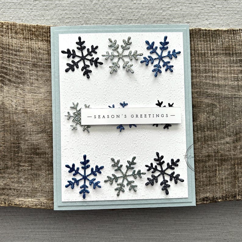 A finished card, from this card making kit, sitting on a wooden board.