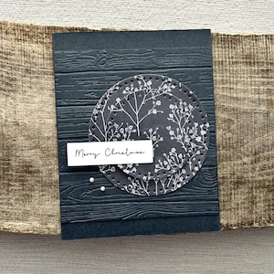 A finished card, from this card making kit, sitting on a wooden board.
