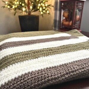 The finished baby blanket, made from this crochet pattern, is draped over a table with Christmas lights.