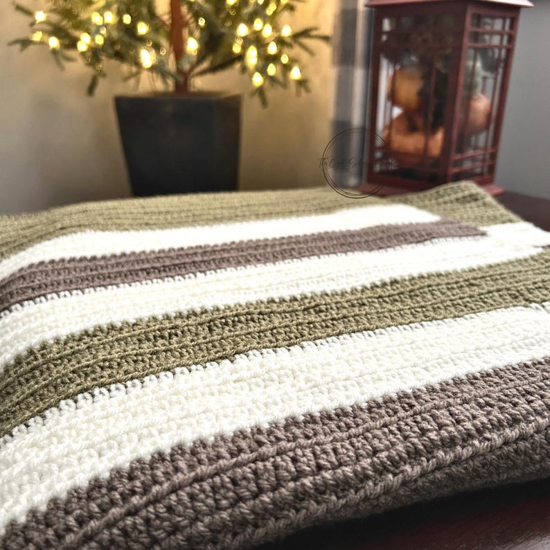 The finished baby blanket, made from this crochet pattern, is draped over a table with Christmas lights.