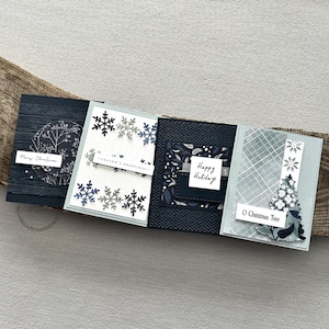 There are 4 finished cards, sitting on a wooden board, to show the finished cards that are included in this card making kit.