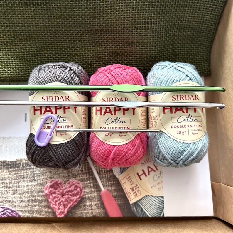 The yarn, used in this crochet pattern, is lying in a box with the pattern and crochet hooks.