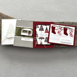 There are 4 finished cards, sitting on a wooden board, to show the finished cards that are included in this card making kit.