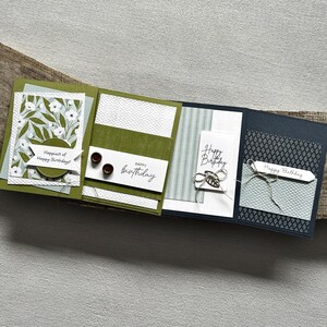 There are 4 finished cards, sitting on a wooden board, to show the finished cards that are included in this card making kit.