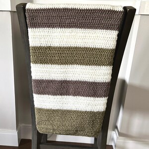The finished blanket, made from this crochet pattern, is lying over a chair.