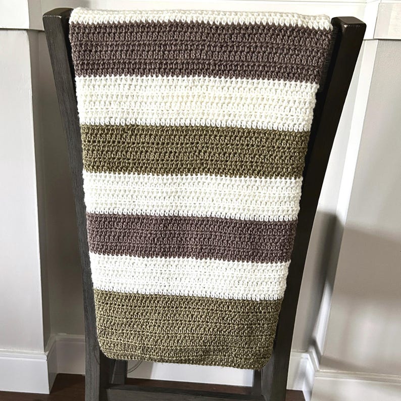 The finished blanket, made from this crochet pattern, is lying over a chair.