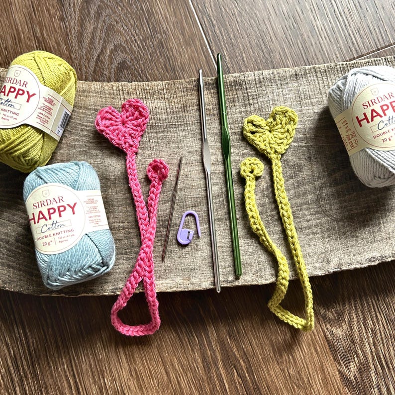 The finished bookmarks, made from this crochet pattern, are lying on a board with yarn and crochet hooks.