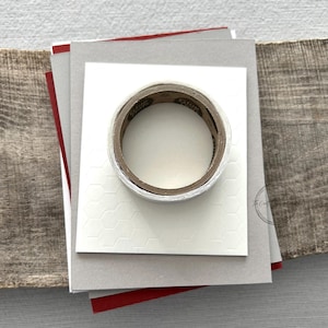 A roll of glue dots and a sheet of pop dots are sitting on a few blank cards. They are included in your card making kit.
