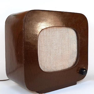 May include: A vintage wooden radio with a brown finish and a speaker covered in a white cloth mesh. The radio has a single knob on the side.
