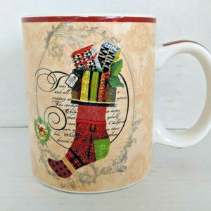 May include: A white ceramic Christmas mug with a red rim and a festive design featuring a stocking filled with presents. The design includes a quote about Christmas and a whimsical illustration of a stocking overflowing with gifts.