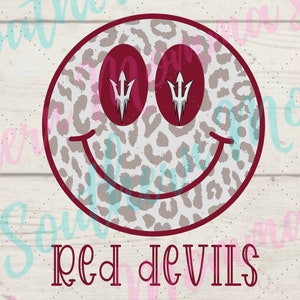 Puede incluir: Una cara sonriente roja y blanca con un patrón de estampado de leopardo. Los ojos son rojos y presentan un diseño de lanza blanca. El texto "RED DEVILS" está debajo de la cara sonriente.