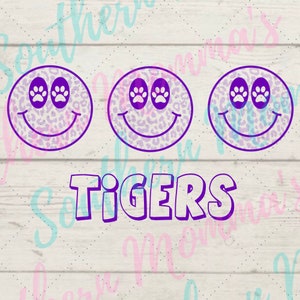 May include: Three purple and white leopard print smiley faces with paw print eyes and the word "TIGERS" in purple outlined letters.