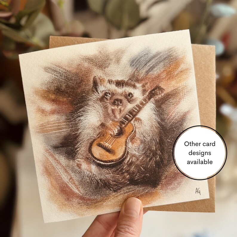 A greeting card featuring a design from one of Alex's original paintings, illustrated with an adorable hedgehog holding a guitar. Printed on 250gsm Tintoretto Gesso paper, it comes with a brown kraft envelope and is packaged in a compostable sleeve. The card is blank inside for your own message.