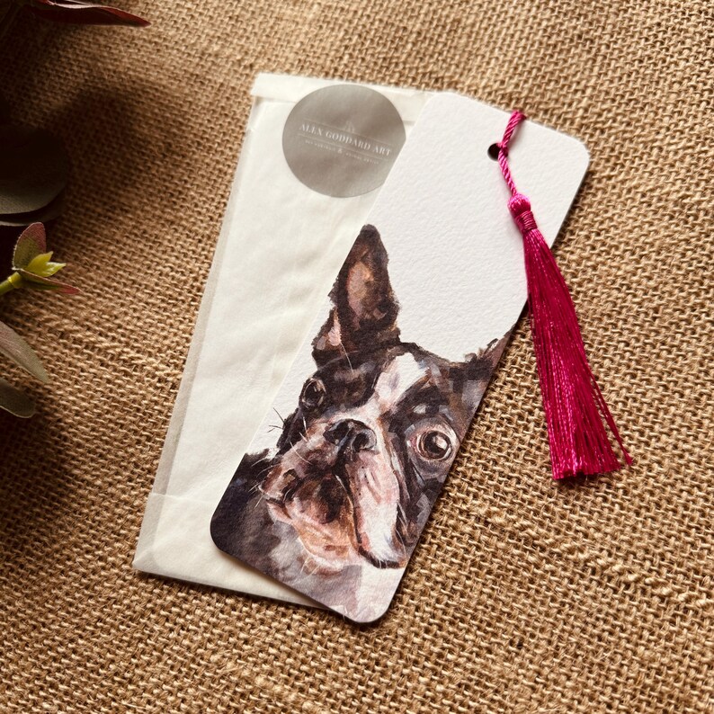 A bookmark showcasing a design from one of Alex's original paintings, featuring a Boston Terrier design. Printed on fine Italian card, it comes with a hot pink coloured tassel color, packaged in a glassine bag, and finished with a stylish branded sticker.