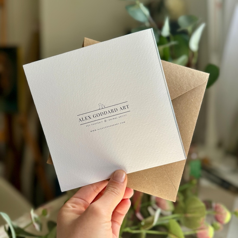 The reverse side of the greeting card showcases an elegant, minimalist design with the artist's logo centered, along with a note that the card includes a brown kraft envelope.
